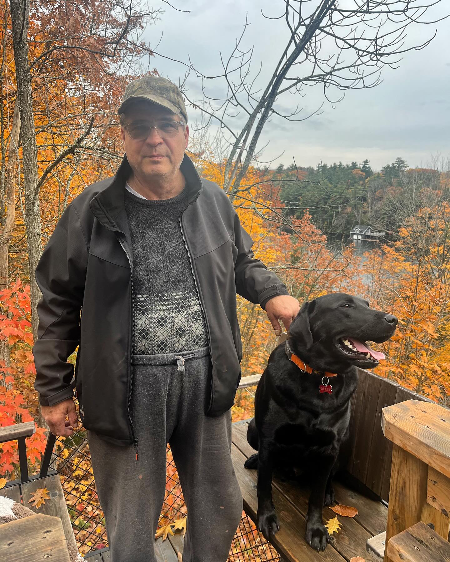 True North Detailing Muskoka owner Jim Schoen and his dog Ollie overlooking a fall Muskoka lake from an observation deck.