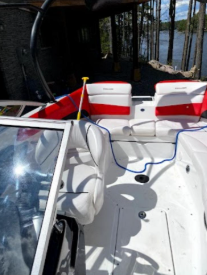 Clean boat interior with white and red seats, showing a red flag and Muskoka lake view in background.