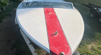 Front-right view of a sparkling white Donzi speedboat with red stripe on a trailer, perfectly clean and polished by True North Detailing Muskoka.