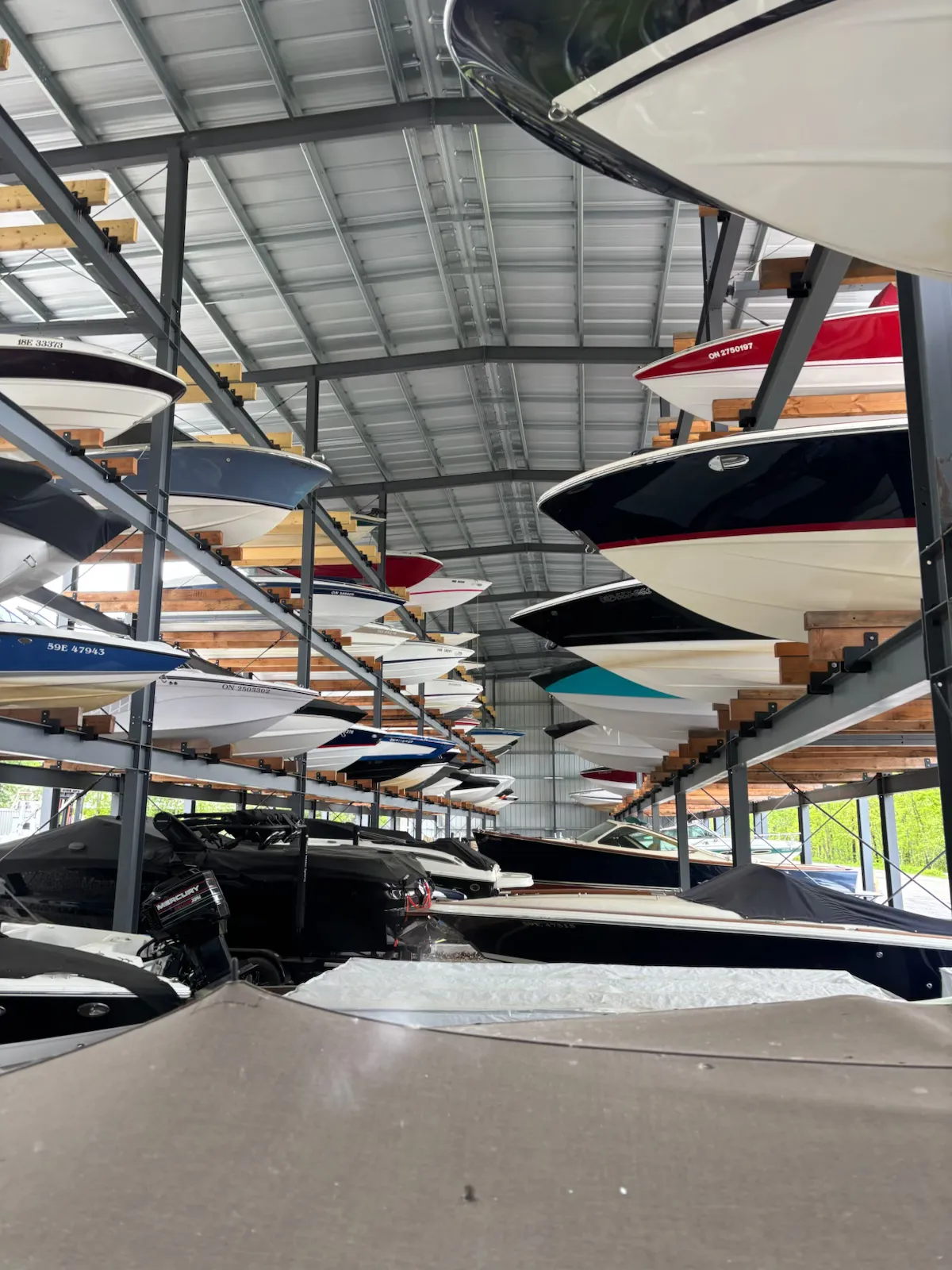 Large indoor boat storage facility with multiple boats racked vertically on shelves, offering secure winter storage solutions.