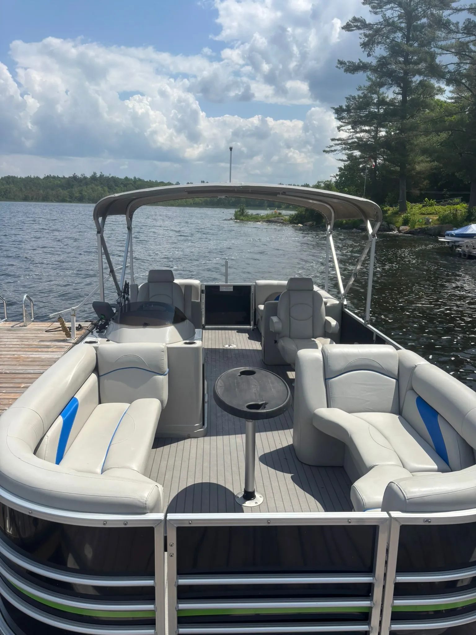 Pristine pontoon boat docked on a Muskoka lake, showcasing a clean interior after professional detailing.
