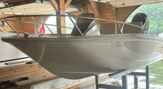 White boat on a lift inside a garage, highlighting the restored shine underneath, by True North Detailing Muskoka.